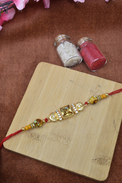 पारंपरिक सोने की परत चढ़ी सोने के रंग के पत्थरों से जड़ी राखी